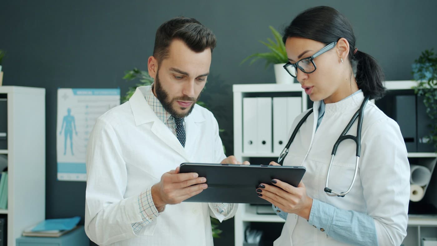 Stock photo: two clinicians in white coats reviewing a case together on a tablet