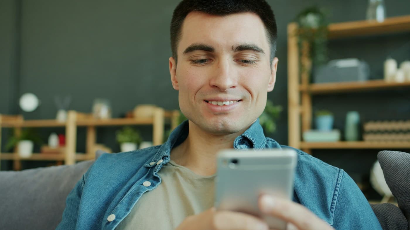 Stock photo: a smiling person using a smartphone at home