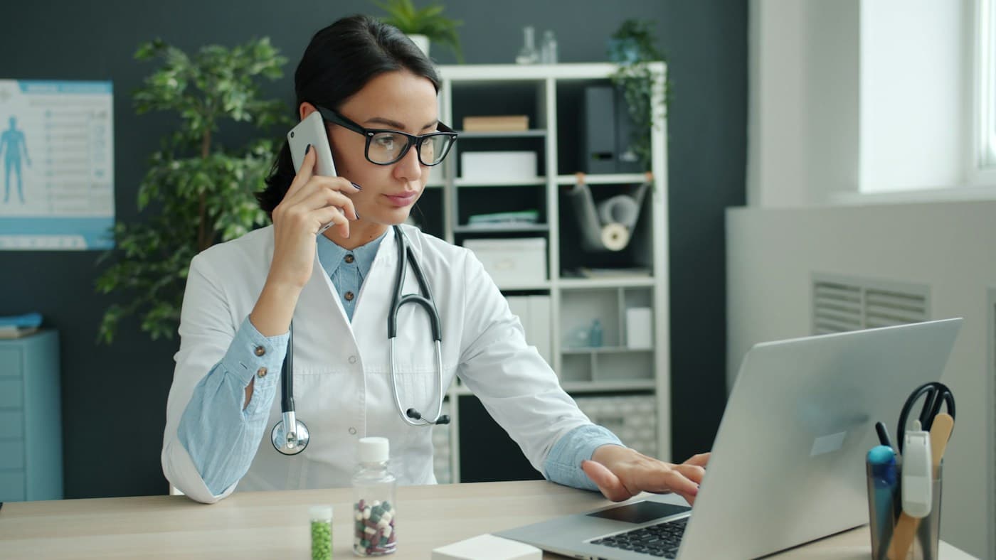 Stock photo: a physician on the phone while working at a laptop in a clinic office