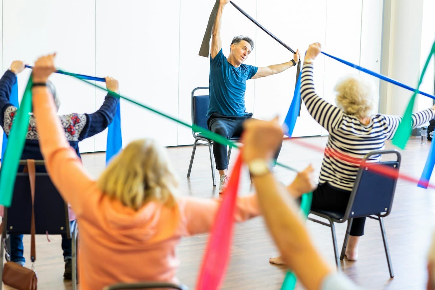 Stock photo: older adults doing seated resistance-band exercises led by an instructor
