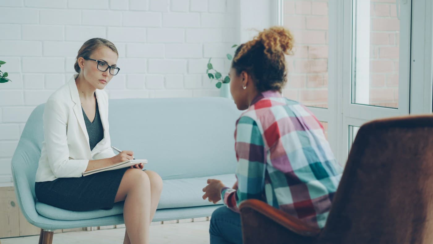 Stock photo: a clinician taking notes while a patient talks in a bright consultation room