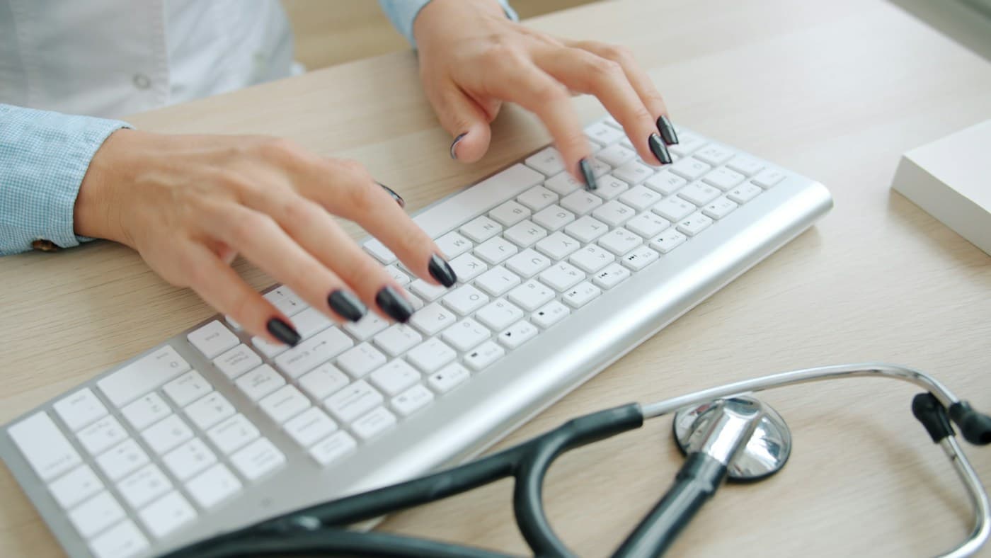 Stock photo: hands typing on a keyboard next to a stethoscope
